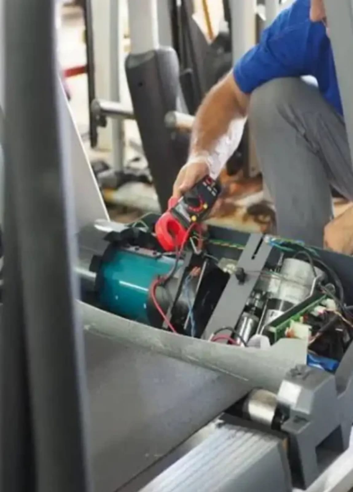 Técnico midiendo el motor de una cinta con multímetro
